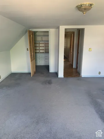 Carpeted flooring, sloped ceiling, built-in closet storage, bi-fold closet door, flush mount ceiling light