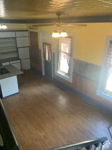 Wood-finish flooring, built-in cabinetry, ceiling fan, recessed lighting, and a kitchen island with cooktop