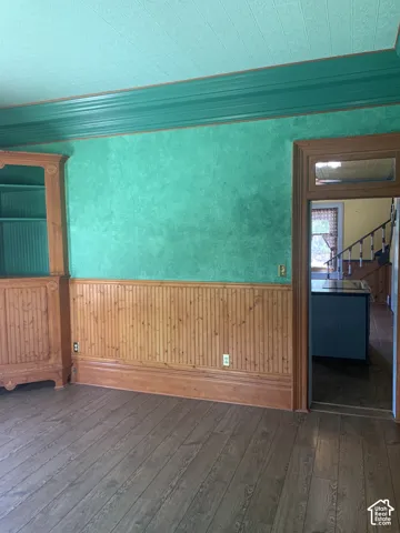 Wood-finish flooring, beadboard wainscoting, and a built-in wooden cabinet with open shelving