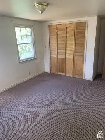 Recessed window with white trim, louvered bi-fold closet doors, and patterned carpet flooring