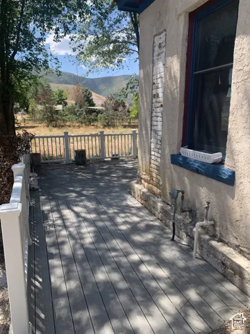 Spacious outdoor deck with composite decking, white railing, stucco exterior, and mountain scenery
