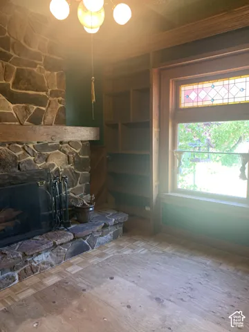 Stone-clad fireplace with a raised hearth, built-in wooden shelving, and a window featuring stained glass accents