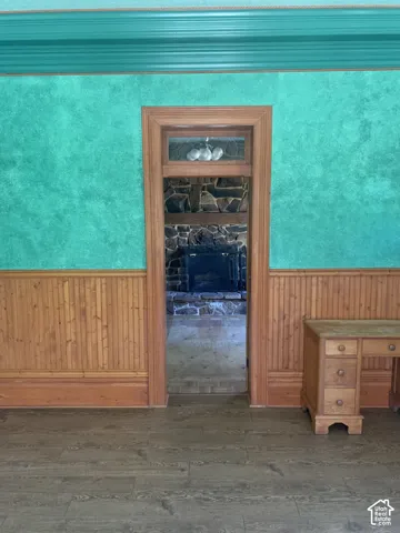 Wood-finish flooring, wood paneling, wood-framed doorway, and a visible stone fireplace