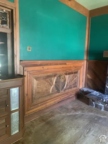 Wood-finish flooring, paneled walls with decorative inlay, built-in corner cabinet with glass-front doors