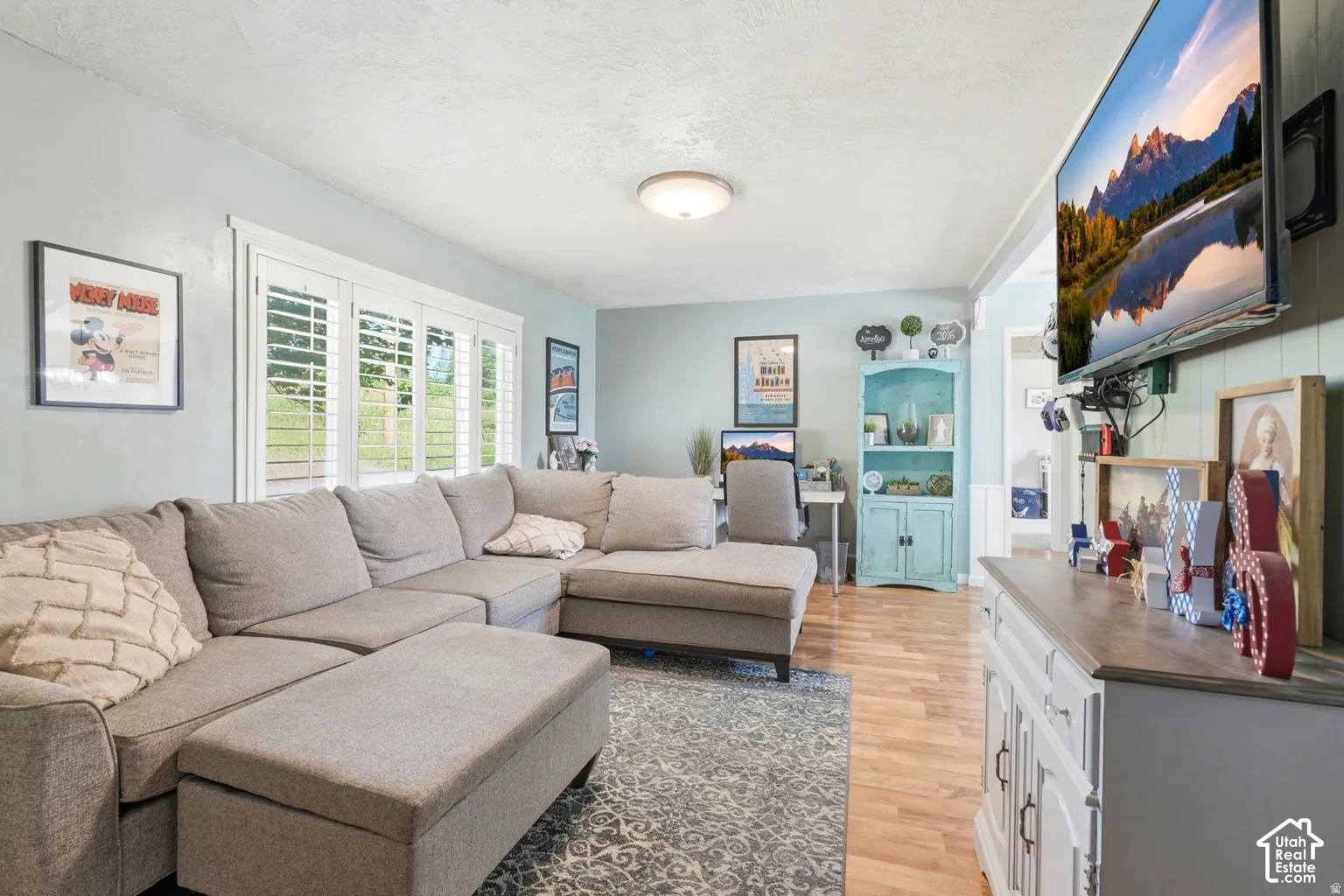 Bay window with white plantation shutters, light wood-finish flooring, and built-in shelving