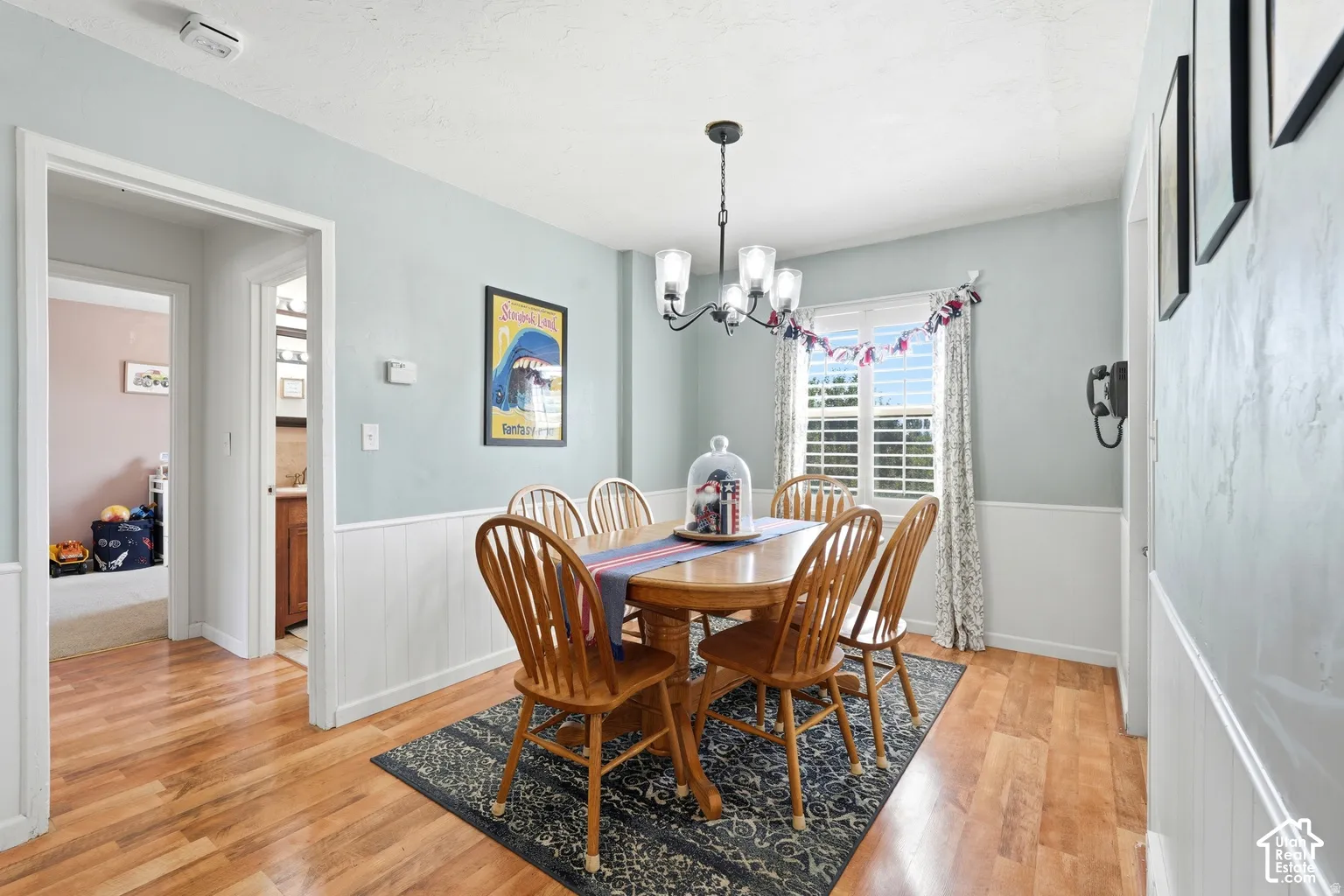 Hardwood-style flooring throughout, white wainscoting, and a multi-pane window with interior shutters