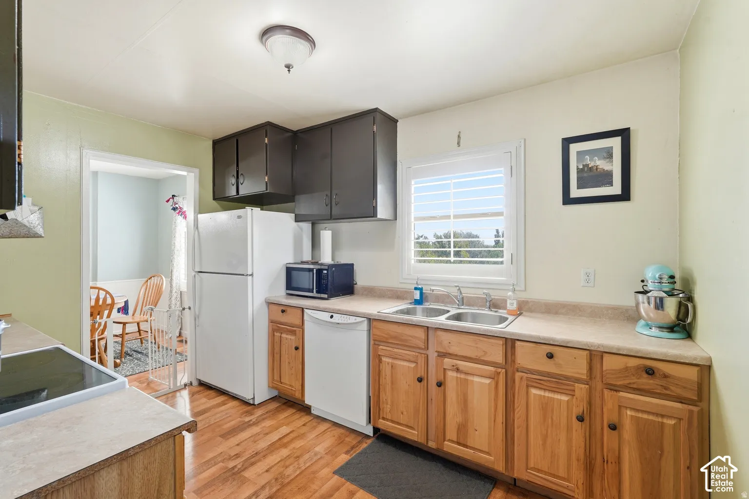 Kitchen with wood-finish flooring, natural wood cabinetry, light-toned countertops, and a dual basin sink