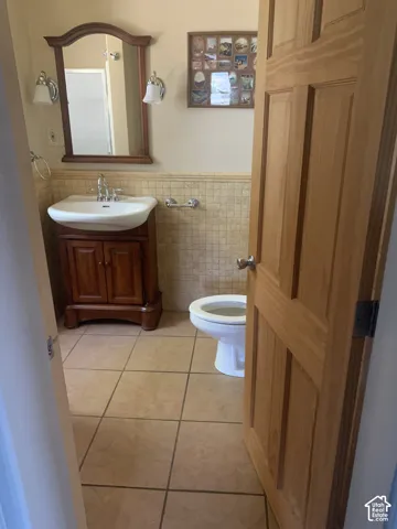 Tile flooring, wood-finish vanity with an integrated sink, and an arched wood-frame mirror