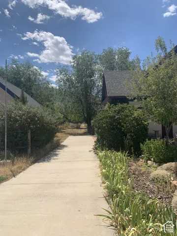 Concrete pathway flanked by established trees and landscaping