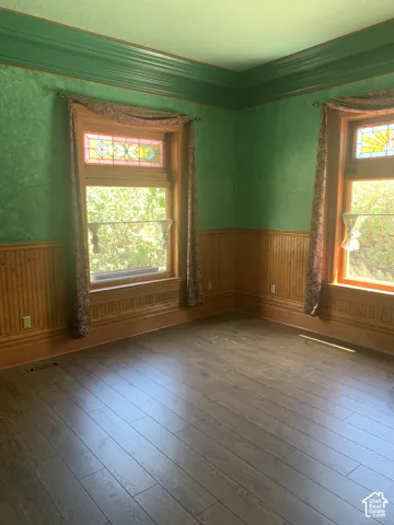 Wood-finish flooring, wainscoting, decorative wall texture, stained glass window accents, and detailed crown molding