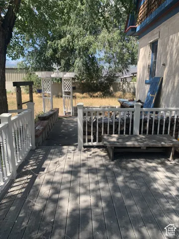 Expansive outdoor deck with white baluster railing, leading to a decorative arbor and a paved pathway
