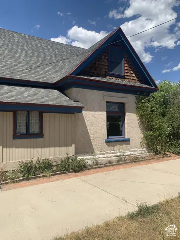 Multi-toned asphalt shingle roofing, stucco exterior, dormer with shingle siding, and concrete hardscaping