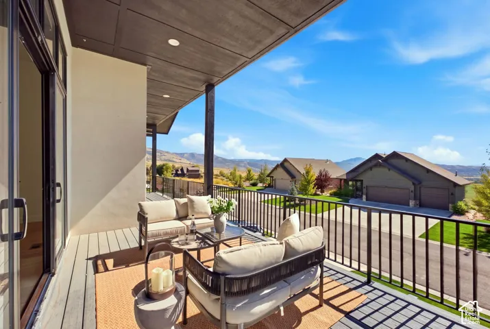 Covered balcony with composite decking, black metal railings, and sliding glass doors
