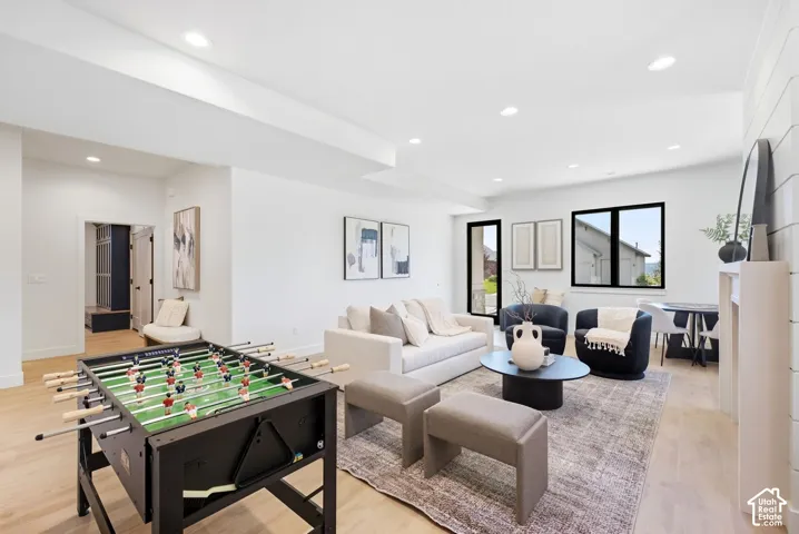 Recessed lighting illuminates the open living area featuring light wood-finish flooring and white walls
