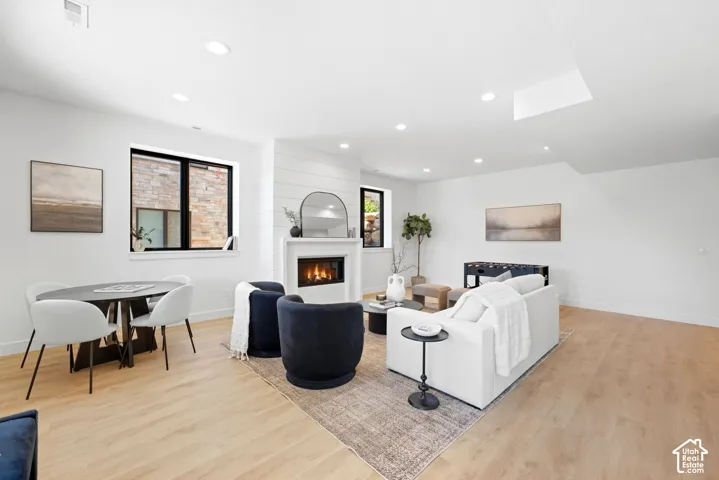 Recessed lighting illuminates the open-concept living space with light wood-finish flooring