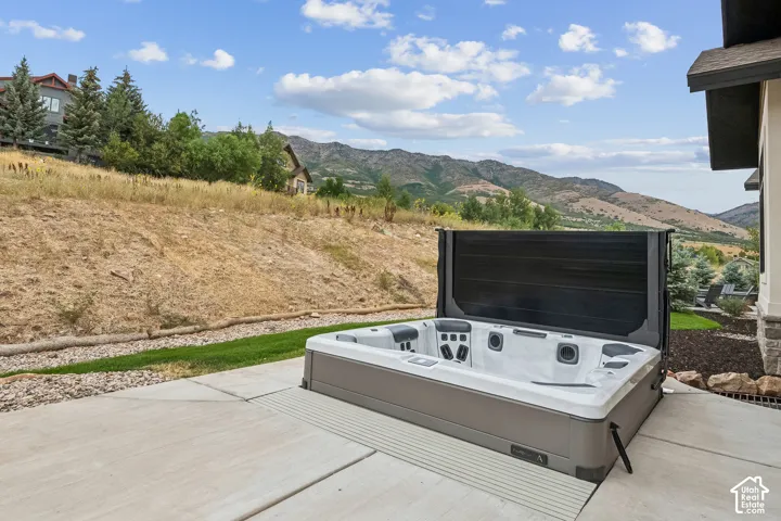 Outdoor spa on a concrete patio, featuring a partial stone and siding exterior