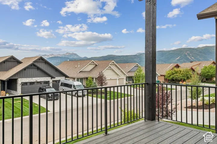 Composite decking with black metal railing overlooking a residential street and distant mountains