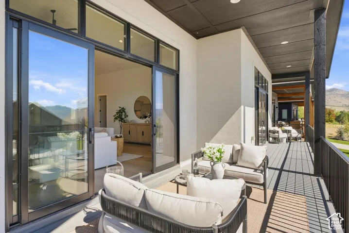 Expansive covered balcony featuring composite decking, black metal railings, and multiple sliding glass doors
