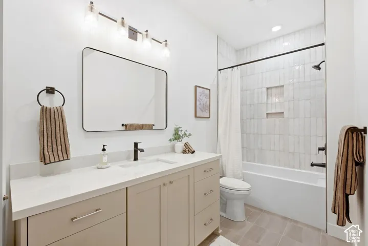 White shaker vanity with a light countertop, black fixtures, and a white tiled shower with a built-in niche