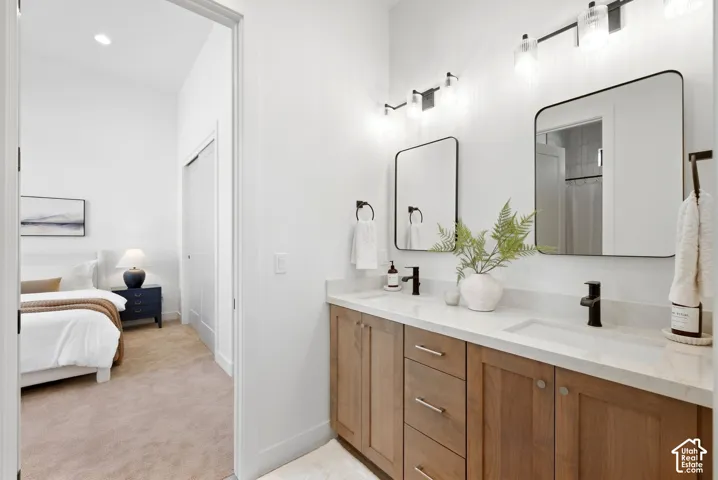 Dual vanities with integrated sinks, quartz countertops, wood-finish cabinetry, and matte black fixtures
