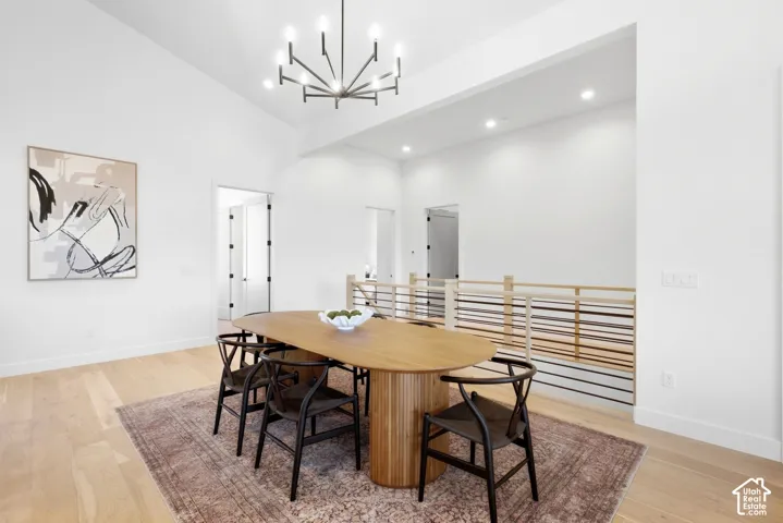 Vaulted ceiling with a contemporary chandelier, recessed lighting, and wood-finish flooring