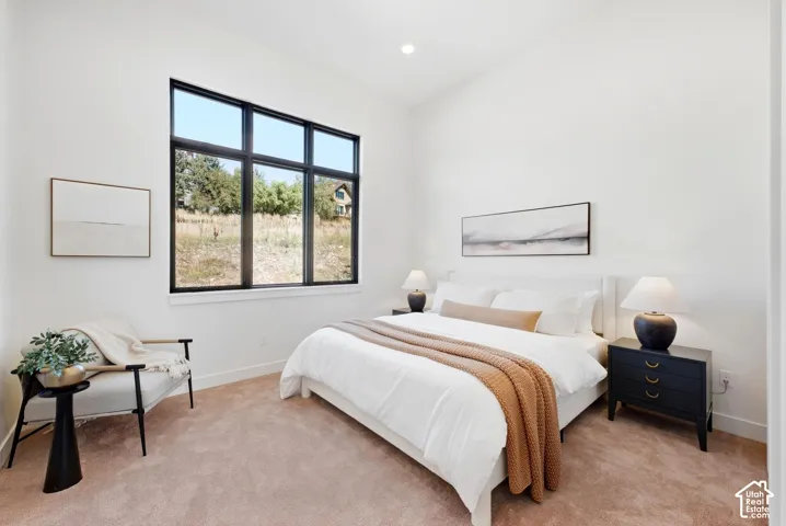 Vaulted ceiling with recessed lighting, large black-framed window, and plush carpet flooring