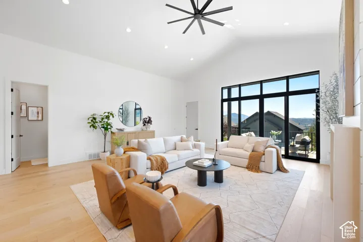 Vaulted ceilings, expansive windows, wood-finish flooring, recessed lighting, and a modern ceiling fan
