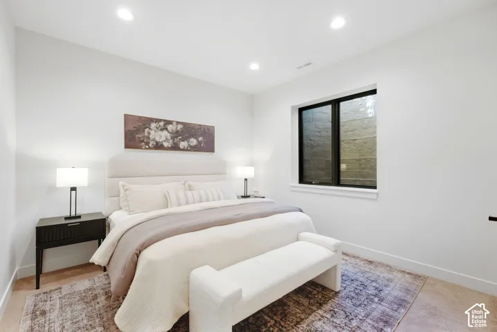 Recessed ceiling lighting, wood-finish flooring, white walls, and a black-framed window