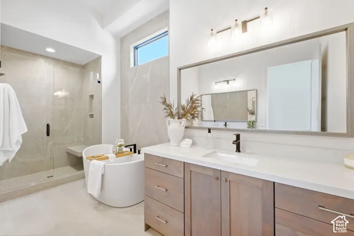 Spacious bathroom featuring a freestanding tub, glass-enclosed shower with bench, wood-finish vanity with stone countertop, and an expansive wall-mounted mirror
