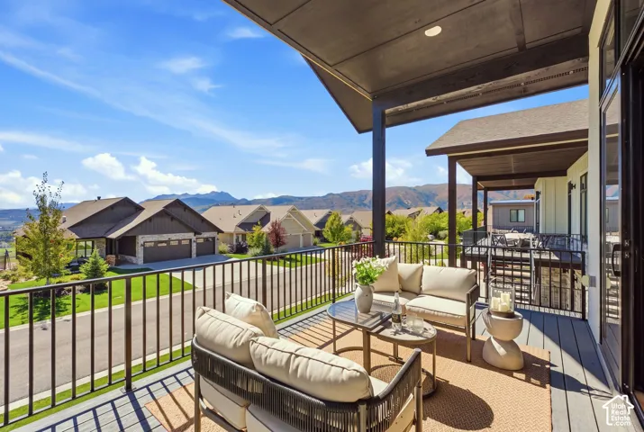 Covered outdoor deck with dark wood-finish flooring, black metal railings, and mountain scenery