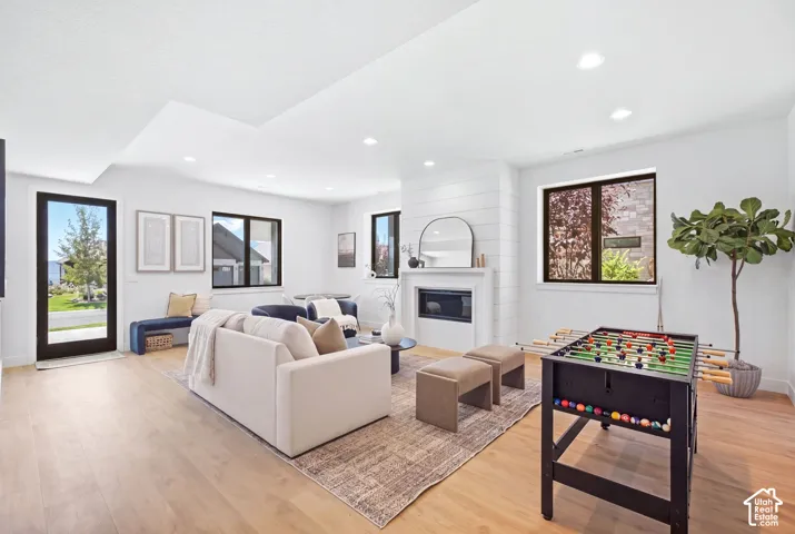 Light wood-finish flooring, recessed lighting, and a fireplace with shiplap detailing