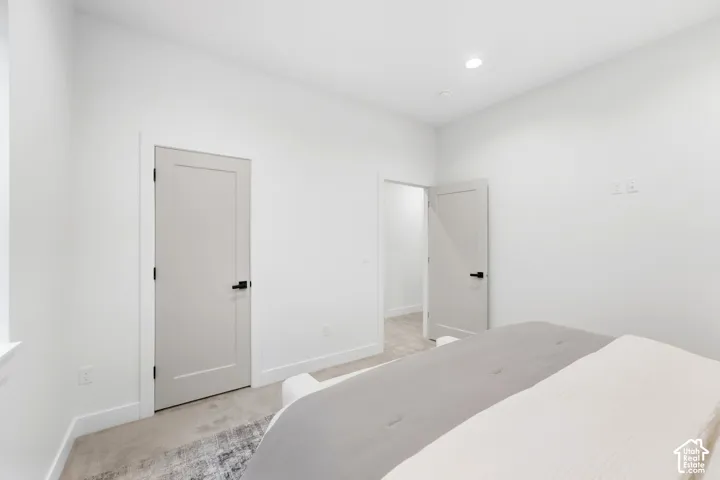 Recessed lighting, light-colored walls, white trim, and a white interior door with black hardware