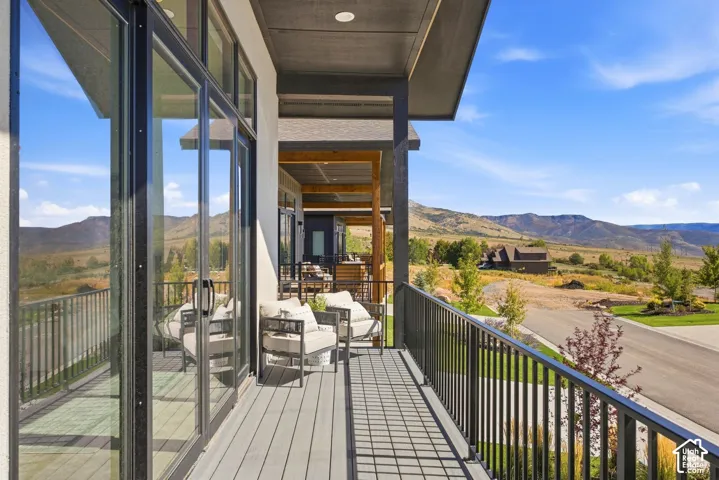Expansive outdoor deck featuring wood-finish decking, black metal railings, and multi-panel sliding glass doors
