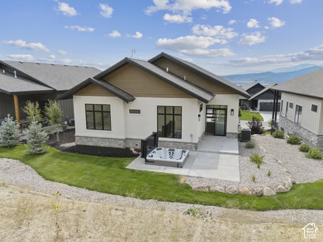 Contemporary stucco exterior with stone accents, dark trim, and a concrete patio