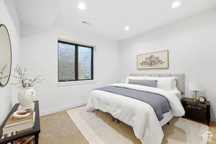 Recessed lighting, large window with black trim, upholstered headboard, and carpeted flooring