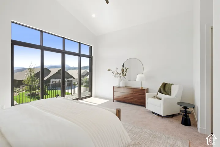 Vaulted ceiling with an expansive window wall and a sliding glass door opening to a balcony with metal railings