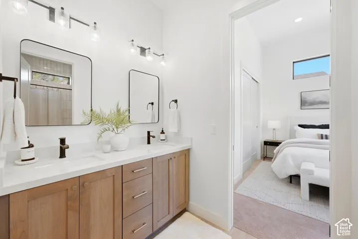 Dual vanity with wood-finish cabinetry, white countertops, and matte black fixtures