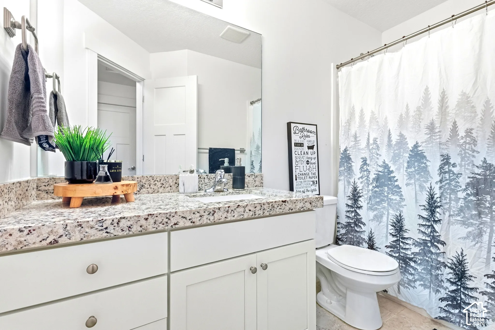 White vanity with granite countertop, integrated sink, and brushed nickel fixtures