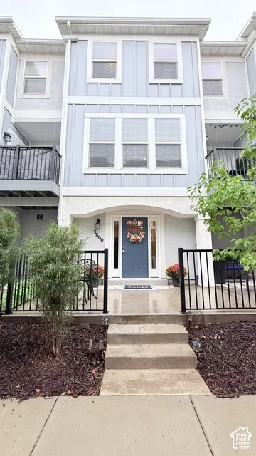 Three-story facade featuring light blue siding with white trim, a recessed entry with a contrasting blue door, and multiple windows with white frames