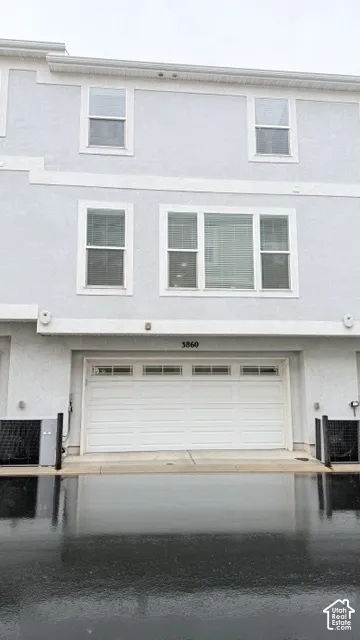 Stucco exterior with multiple windows, an integrated garage, and a concrete driveway
