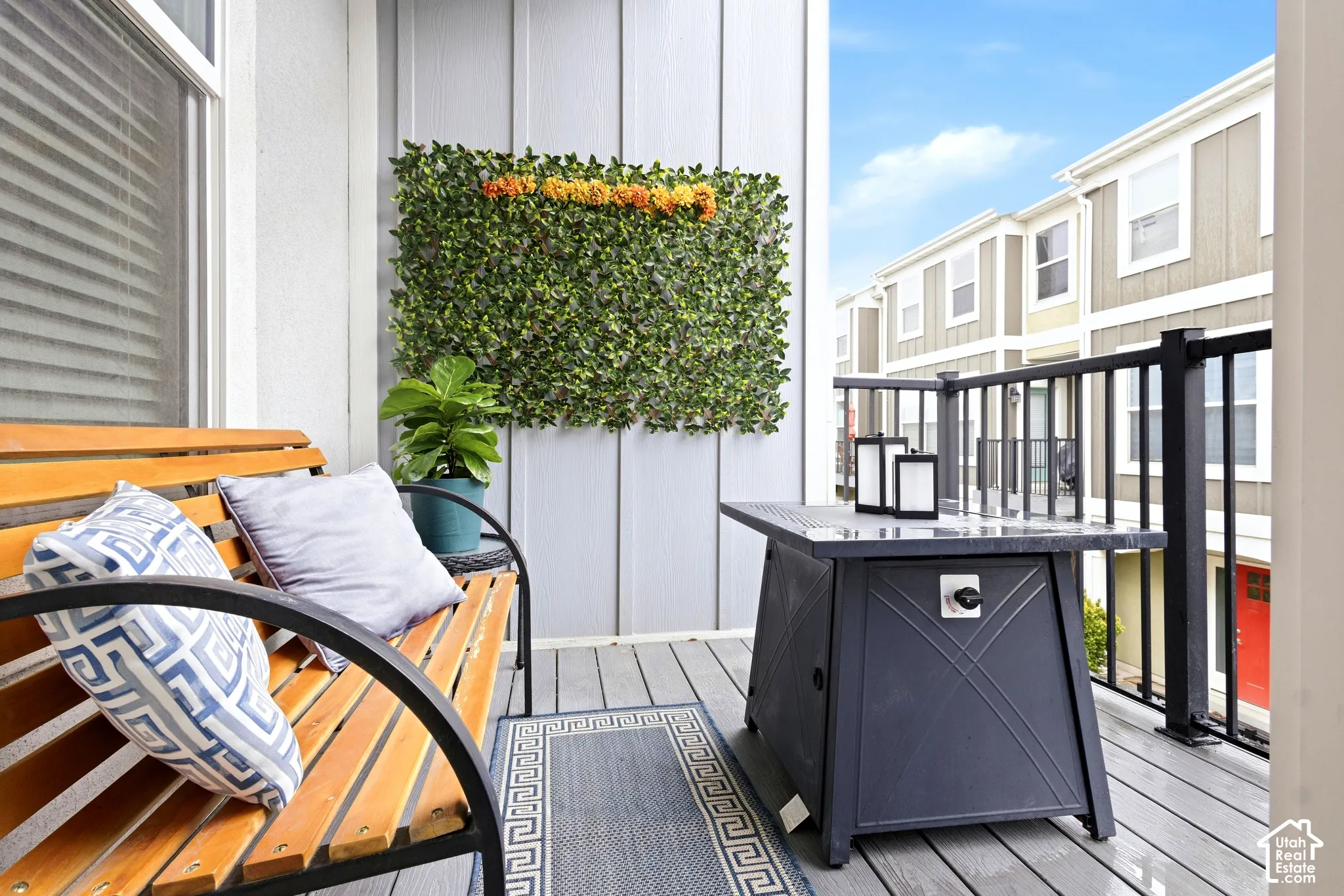 Balcony featuring a planked deck, black metal railing, and vertical wall paneling