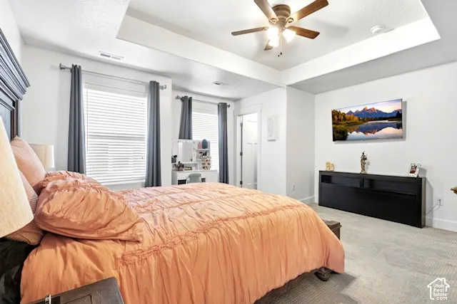 Recessed ceiling with a ceiling fan, carpeted flooring, and window blinds