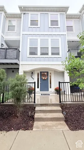Three-story facade featuring light blue siding with white trim, a recessed entry with a contrasting blue door, and multiple windows with white frames