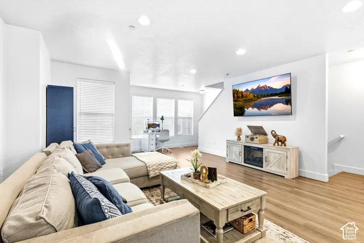 Open-concept living space featuring wood-finish flooring, recessed lighting, and large windows with blinds