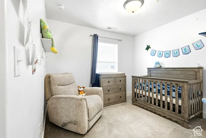 Neutral wall color, window with blinds, overhead light fixture, wood-finish crib, and wood-finish dresser