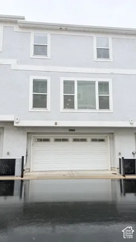 Stucco exterior with multiple windows, an integrated garage, and a concrete driveway