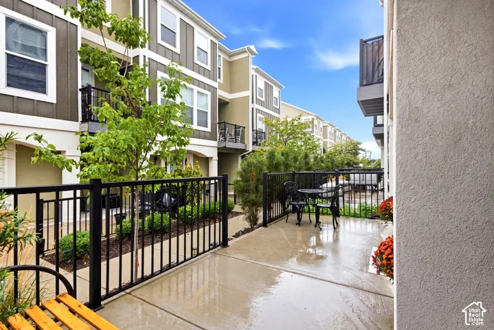 Private patio area with concrete surfacing, black metal fencing, and established perimeter landscaping