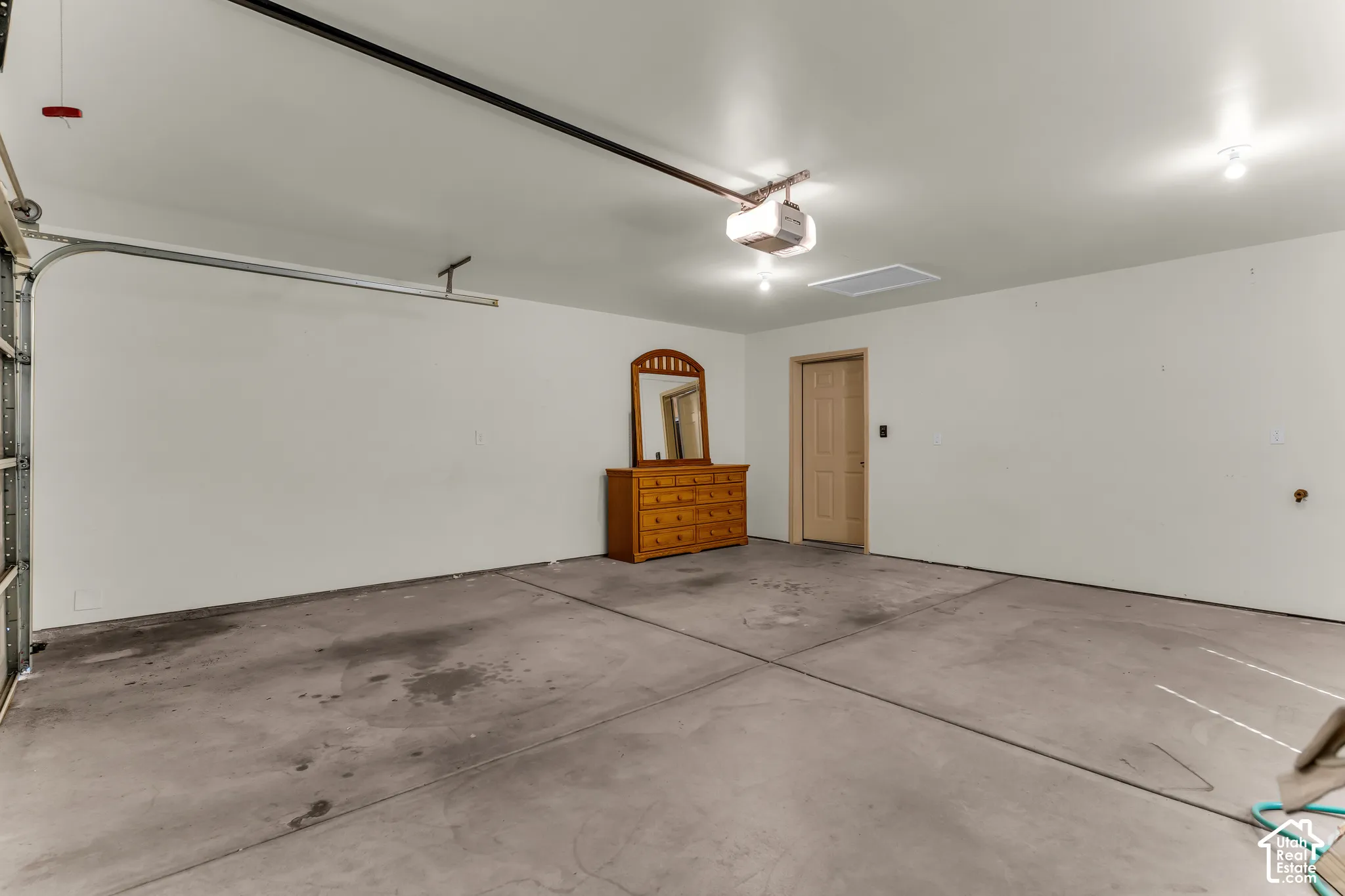 Spacious garage with concrete flooring, overhead lighting, and an automatic garage door opener