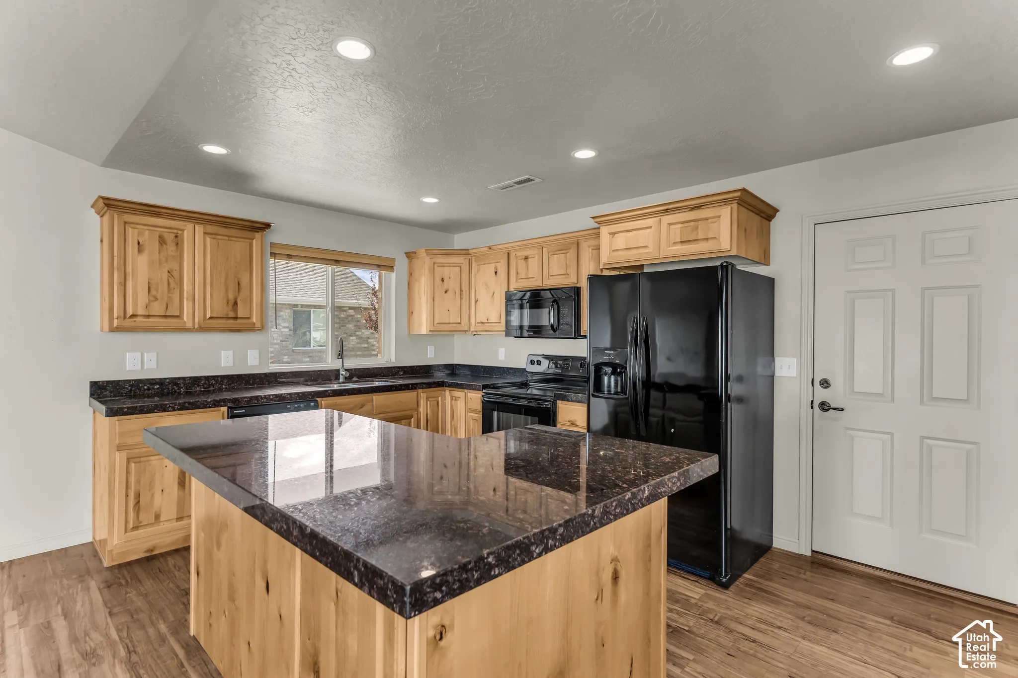 Kitchen featuring wood-finish flooring, recessed lighting, and a kitchen island with a dark countertop