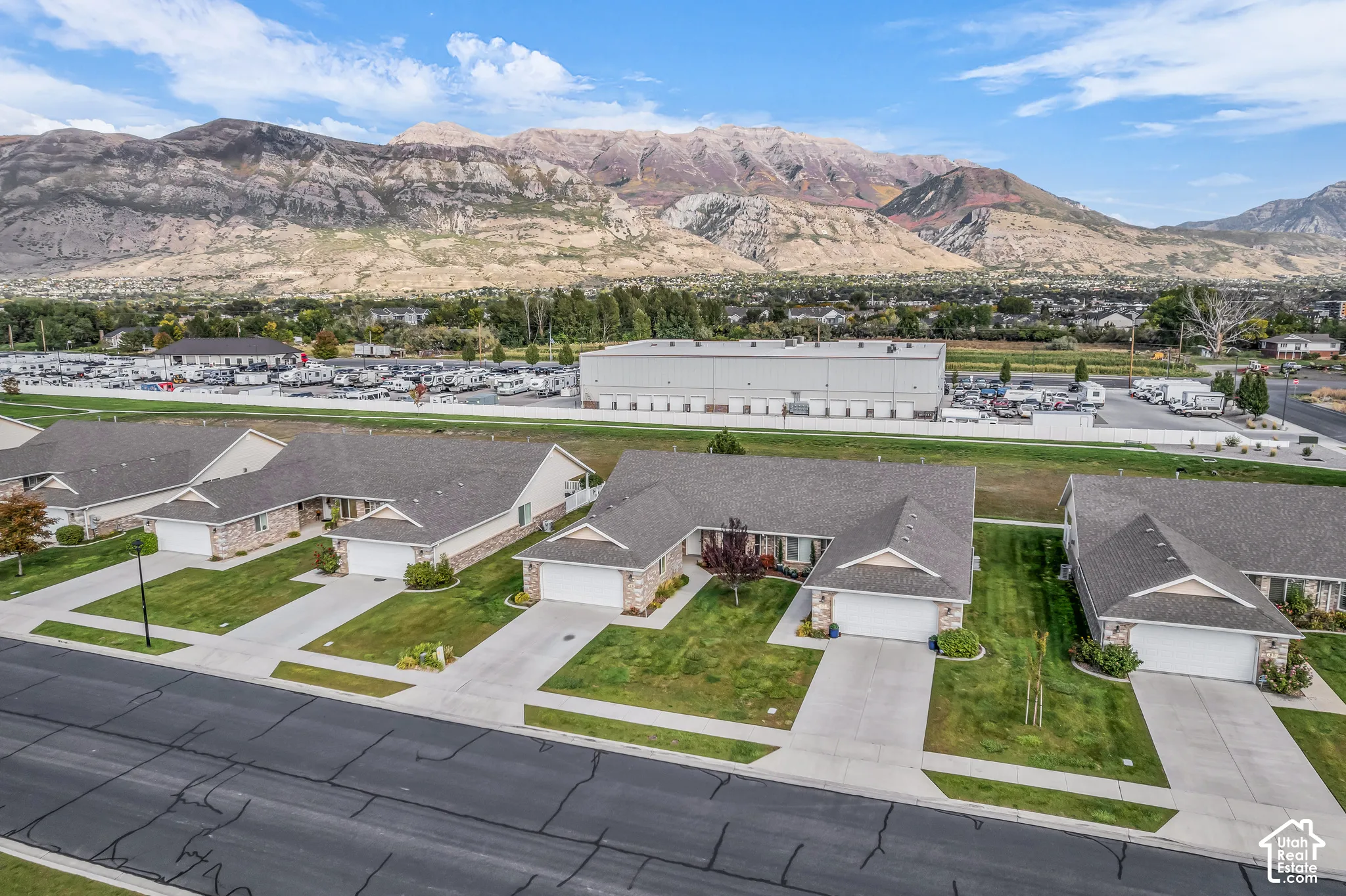 Mountain backdrop, multiple single-story residences, stone veneer exteriors, paved driveways, and attached garages